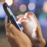 CLose up on the hand of young woman sing smart phone hand hold, tapping the screen - social network, communicaiton, technology concept