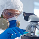 Male chemist in protective clothing studying new fluid in lab