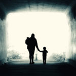 A single mother and two children walk into the light