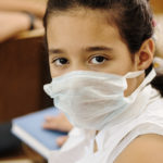 Schoolgirl with medicine mask on face, in classroom, against: virus, ill, epidemic, plague, flu