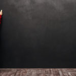 Image of a little pretty child standing near blackboard and drawing on it.