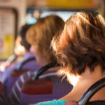 Passengers sit in a bus on a sunny summer day close-up.