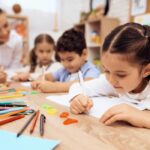 Children write in notebooks with a pen.