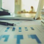 Business concept with copy space. Office desk table with pen focus and analysis chart, computer, notebook, cup of coffee on desk.Vintage tone Retro filter effect.Selective focus.